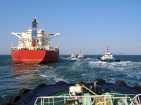 Ore carrier with three tugboats
